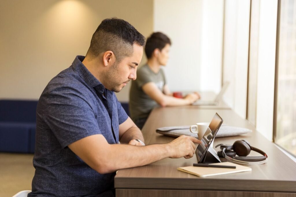 Two men working on devices in a modern office setting, emphasizing technology and collaboration.